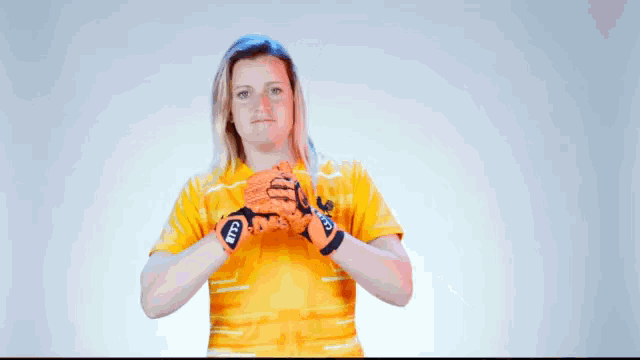 a woman wearing a yellow shirt and orange gloves with the letters ntf on them