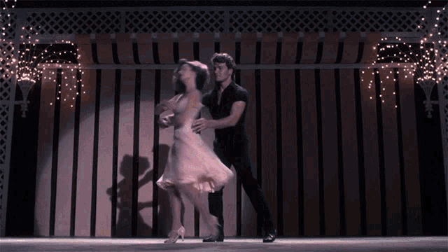 a man and woman are dancing on a stage in front of a striped wall