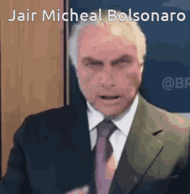 a man in a suit and tie is giving a speech in front of a sign that says jair micheal bolsonaro .