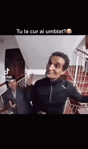 a man is standing on a set of stairs and making a funny face while another man looks on .