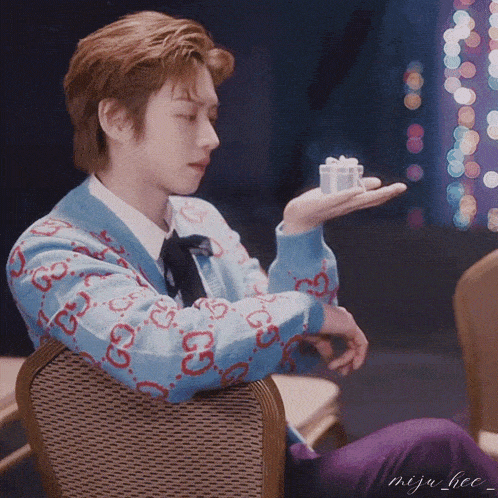a man sitting in a chair holding a small gift in his hand