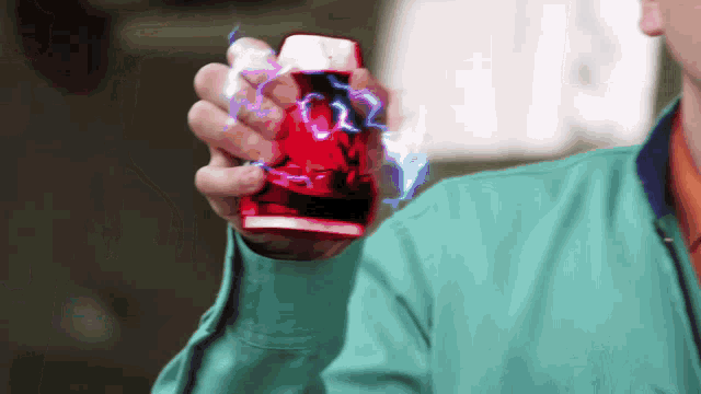 a man in a green jacket is holding a red cup in his hand