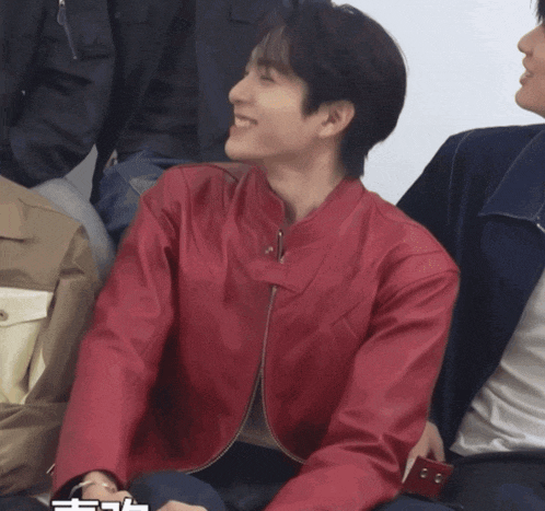 a man in a red leather jacket sits next to another man in a blue jacket