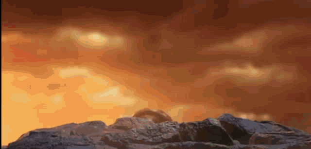 a group of rocks sitting on top of each other in front of a cloudy sky .