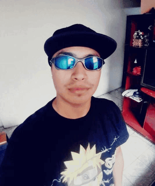 a man wearing sunglasses and a black hat stands in a living room