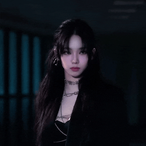 a woman with long black hair and a nose ring is wearing a black jacket and a choker necklace .