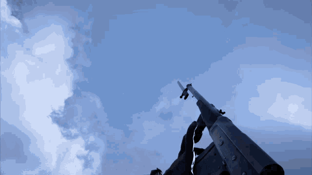 a silhouette of a person holding a gun against a cloudy sky