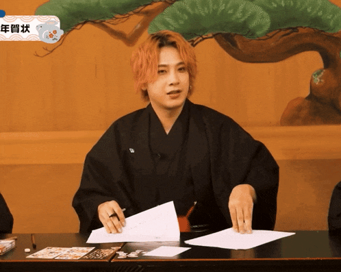 a man in a kimono holds a piece of paper in front of him