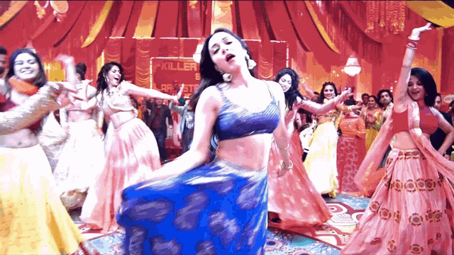 a woman in a blue top is dancing in front of a sign that says " killer "