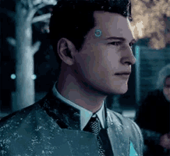 a man in a suit and tie is standing in the dark .