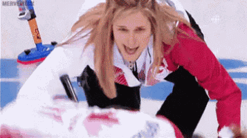 a woman in a red and white jacket is playing curling on a ice rink .