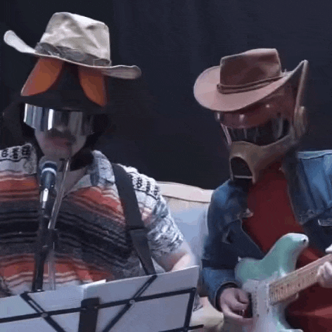 a man in a cowboy hat is playing a guitar next to another man in a cowboy hat and helmet .