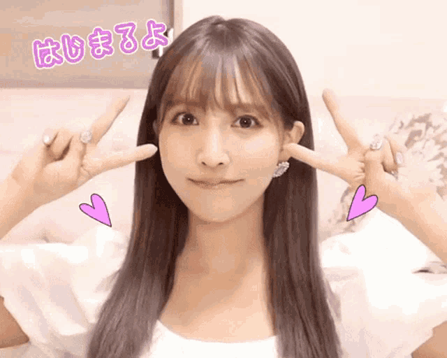 a woman making a peace sign with her fingers and a pink heart behind her