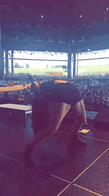 a person is standing on a stage in front of a crowd in a stadium .