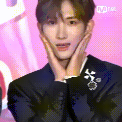 a man in a suit is covering his face with his hands and looking surprised .