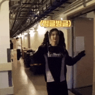 a woman is standing in a hallway wearing pigtails and a hoodie .
