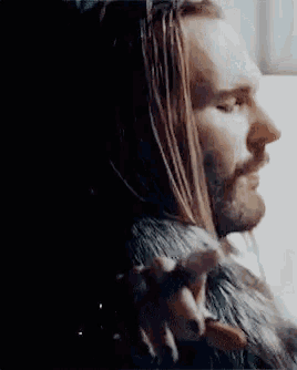 a close up of a man with long hair and a beard holding a rabbit .