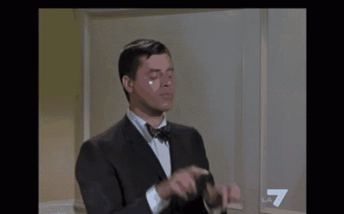 a man in a suit and bow tie clapping his hands