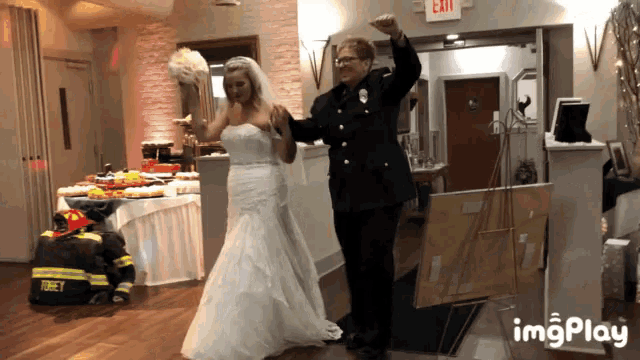 a bride and groom are dancing in front of a fireman and an exit sign
