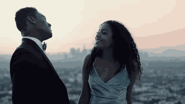 a man in a tuxedo and a woman in a blue dress are looking at each other