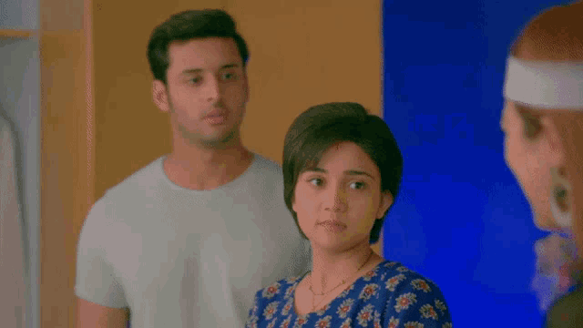 a man and a woman are standing next to each other looking at something