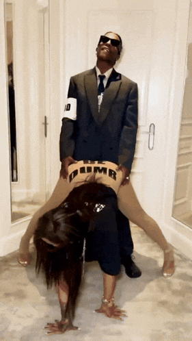 a man in a suit and tie holds a woman in a dumb shirt