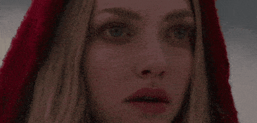 a close up of a woman 's face with a red hood on her head