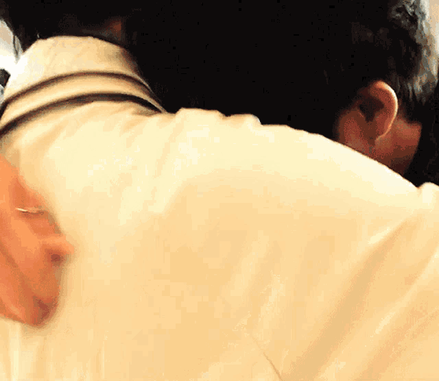 a man in a white shirt is hugging another man with a stethoscope around his neck