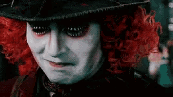 the mad hatter from alice in wonderland is wearing a black hat and red wig .