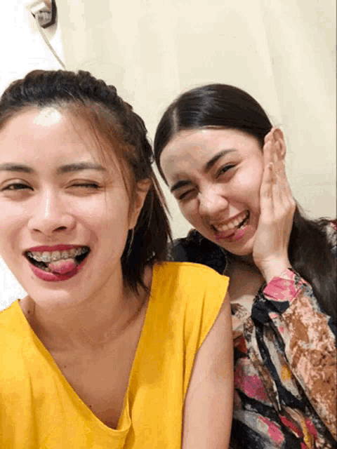 a woman with braces on her teeth is making a funny face next to another woman