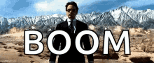 a man in a suit and tie is standing in front of a mountain with the word boom written above him .