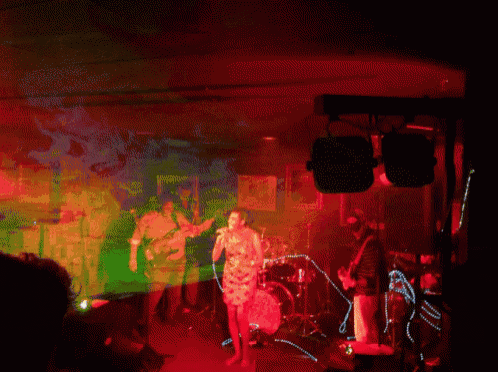 a group of people playing instruments in a dark room with red and green lights