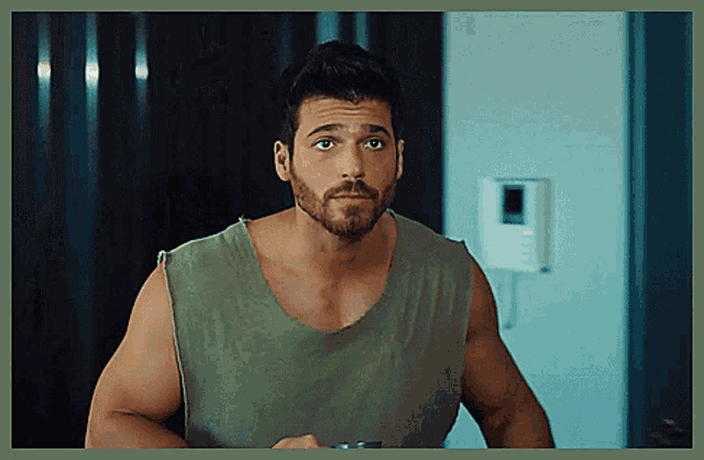 a man with a beard and a green tank top