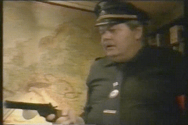 a man in a police uniform is holding a gun in his hand .