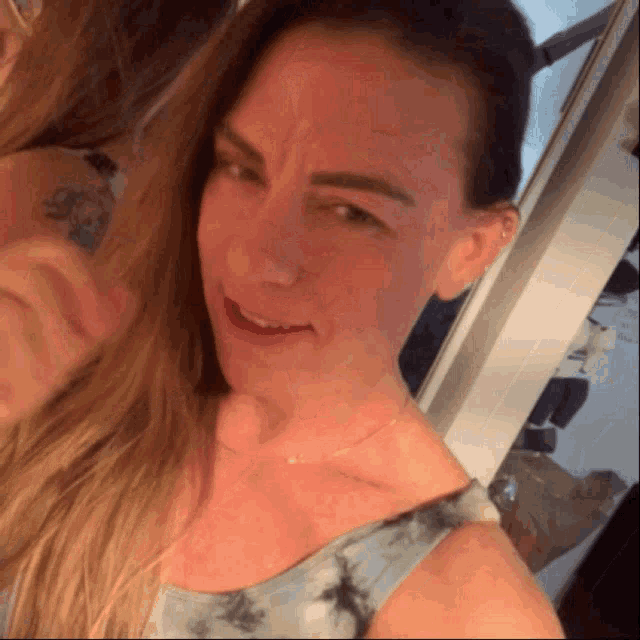 a woman taking a selfie with another woman in the mirror