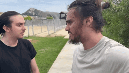two men are standing next to each other and one has a beard