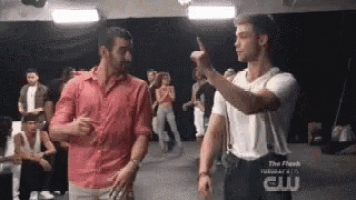 two men are standing next to each other in a room and one of them is pointing at the other .