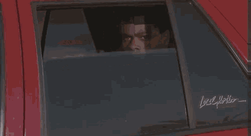 a man is standing on the sidewalk next to a red car holding a plate .