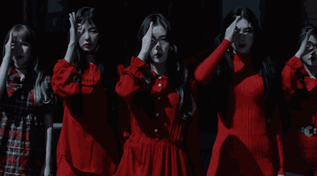 a group of women in red dresses are standing in a line