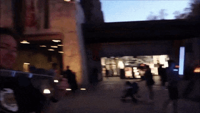 a blurry picture of people walking down a street with a sign that says ' coca cola '