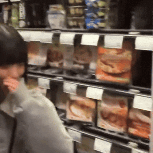 a woman is standing in front of a shelf with boxes of food