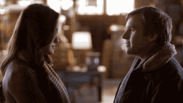 a man and a woman look at each other in a dark room