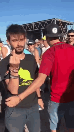 a man wearing a black shirt with a cat on it is giving the middle finger