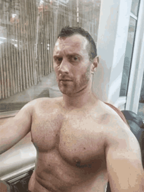 a shirtless man with a beard is taking a selfie