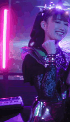 a girl with a crown on her head is smiling in a dark room