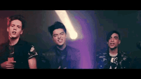 a group of young men are standing next to each other in a dark room .