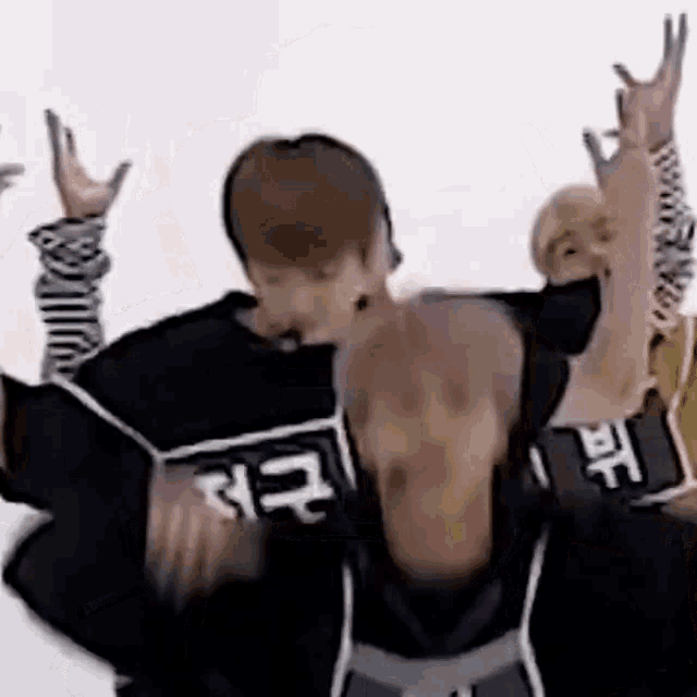 a man without a shirt is dancing in front of a group of people with their arms in the air .