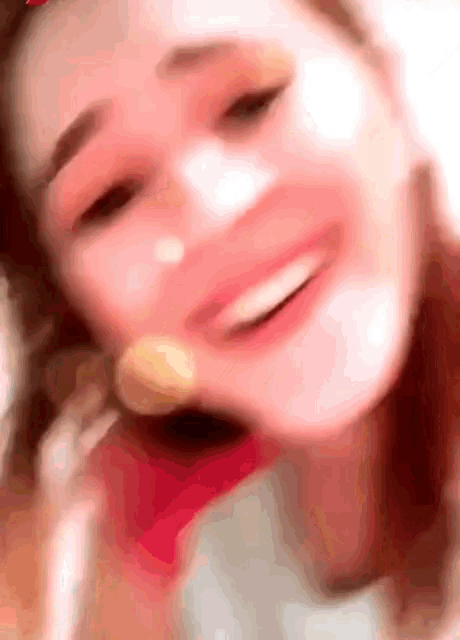 a close up of a woman 's face smiling with a blurred background