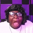 a man wearing glasses and a black hat is sticking out his tongue .