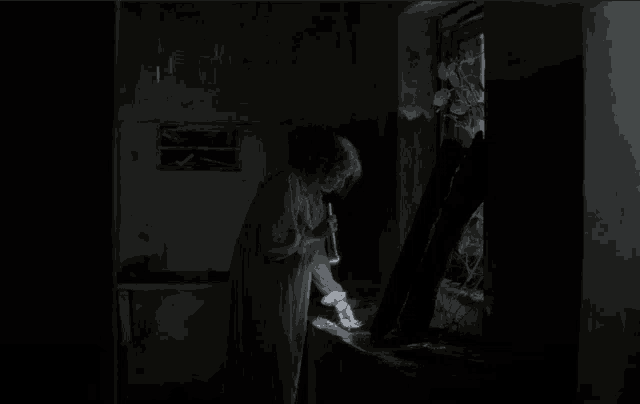 a woman standing in a dark room with a flashlight in her hand